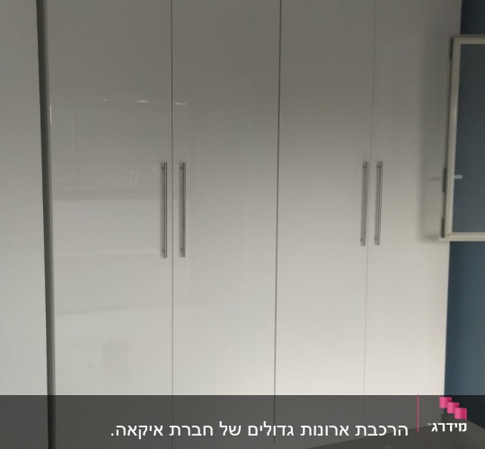 ארון לבן עם ידיות מתכת על רצפה אפורה